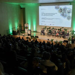 Na zdjęciu widoczna jest część widowni wraz z uczestnikami. Dodatkowo widać scenę, na której jest pięciu prelegentów Panelu 1 i moderator. Na ekranie jest slajd z tytułem panelu: „Panel I: Przyszłość regionów górniczych po 2027 roku – wyzwania i kierunki działań w nowej perspektywie unijnej oraz imionami i nazwiskami prelegentów i moderatora. Na scenie są także małe stoliczki, kwiaty doniczkowe, a w tle - baner Regionalnego Obserwatorium Procesu Transformacji. 