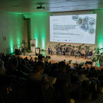 Na zdjęciu widoczna jest część widowni wraz z uczestnikami. Dodatkowo widać całą scenę, na której jest sześciu prelegentów Panelu 2 i moderator siedzący na fotelach. Na ekranie jest slajd z tytułem panelu: „Panel II: Zawodowy restart – jak skutecznie wspierać pracowników sektora węglowego. Nowe możliwości zawodowe dla pracowników kopalń i firm okołogórniczych” oraz imionami i nazwiskami prelegentów i moderatora. Na scenie są także małe stoliczki, kwiaty doniczkowe, a w tle - baner Regionalnego Obserwatorium Procesu Transformacji. 