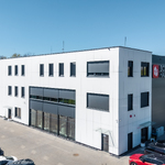 Widok z góry na budynek produkcyjno-biurowy firmy BOX HAUS z halą, częścią biurową, parkingiem i samochodami przed obiektem.