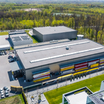 Widok z lotu ptaka na kompleks produkcyjno-magazynowy firmy BOX HAUS z halami, parkingami, składowanymi materiałami oraz otaczającymi terenami zielonymi.